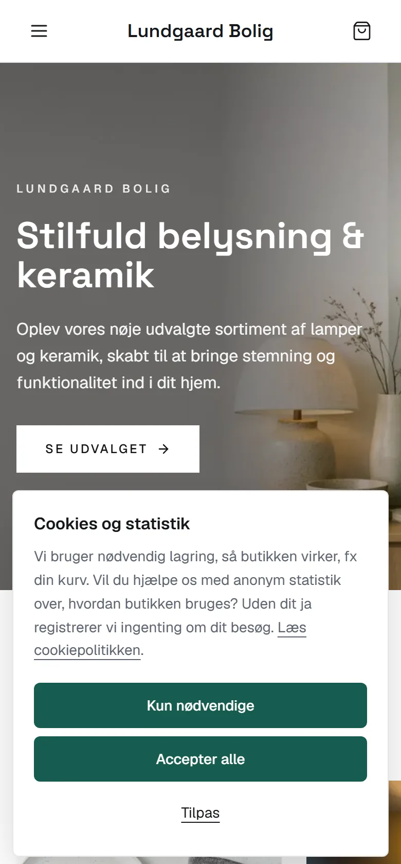 Demobutikken Lundgaard Bolig på en telefon ved første besøg: cookie-banneret 'Cookies og statistik' med knapperne Kun nødvendige, Accepter alle og Tilpas.